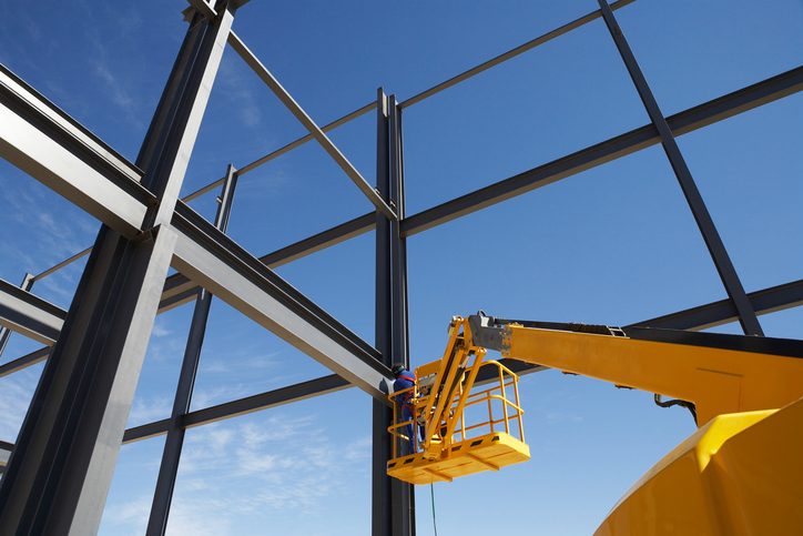 Welder working from cherry picker on warehouse construction