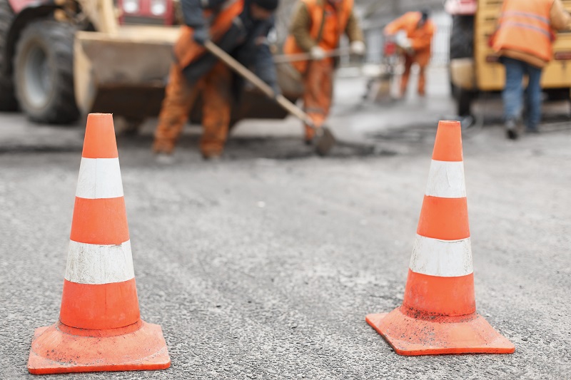 road workers repair the road, cones in foreground