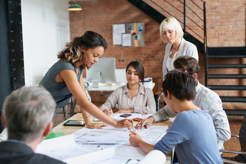 Multi ethnic group architects working on plans at business boardroom