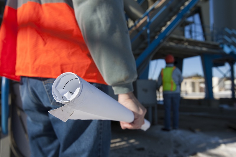 Engineer holding a blueprint at industrial plant